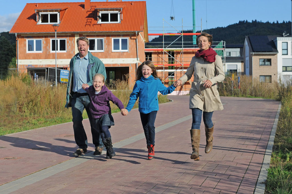 Fröhliche Familie geht in einem Wohngebiet spazieren