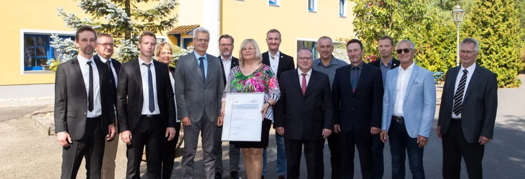 Geschäftsführerin Sylvia Schenker mit dem TSM-Zertifikat, umgeben von Gesellschaftern und Prüfern vor dem Firmensitz der EVSE in Saalau