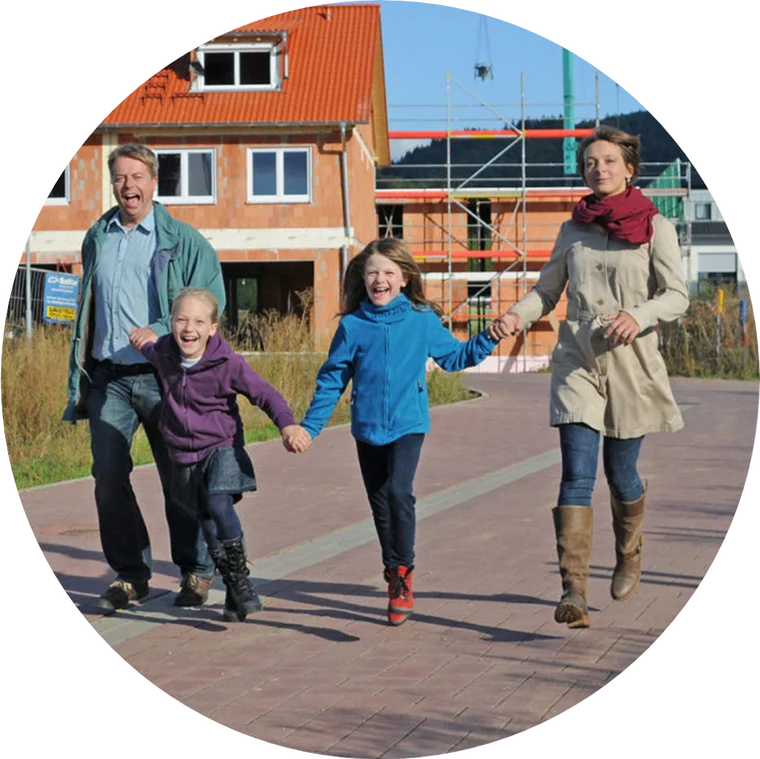 Familie läuft fröhlich durch ein Neubaugebiet in der Region – Energieversorgung mit Heimvorteil